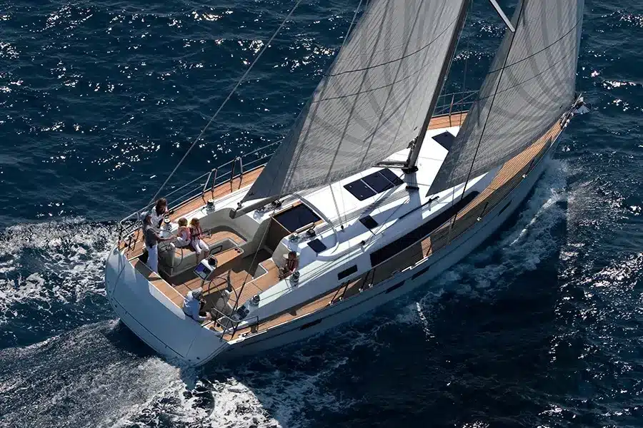 Luftaufnahme eines luxuriösen Katamarans, der auf klarem, blauem Wasser kreuzt. An Deck sind vier Personen zu sehen, die die Fahrt genießen.
