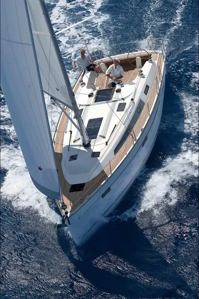 Luftaufnahme von zwei Männern, die eine Segelyacht mit voll gehisstem Segel über den tiefblauen Ozean gleiten.