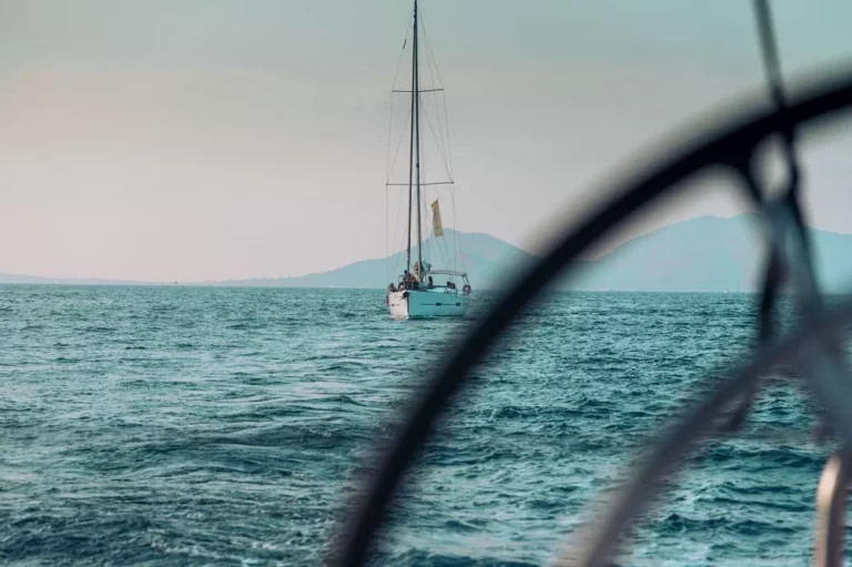 Ein ruhiger Blick auf ein Segelboot auf dem Meer, eingerahmt von einem verschwommenen kreisförmigen Umriss, der den Eindruck erweckt, als würde man es während einer Segelreise durch das Bullauge eines anderen Bootes betrachten.
