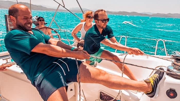 Crew arbeitet zusammen am Segel setzen, Spaß am Segeln