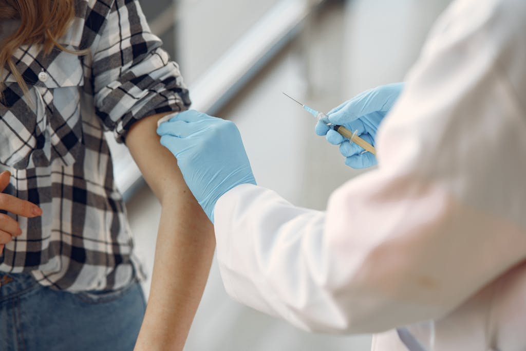 A medical professional giving a vaccination to a patient indoors, emphasizing healthcare. Impfung