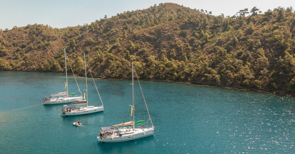 Drei weiße Segelboote in türkisfarbener Bucht umgeben von Wäldern – segeln türkei mit sailwithus