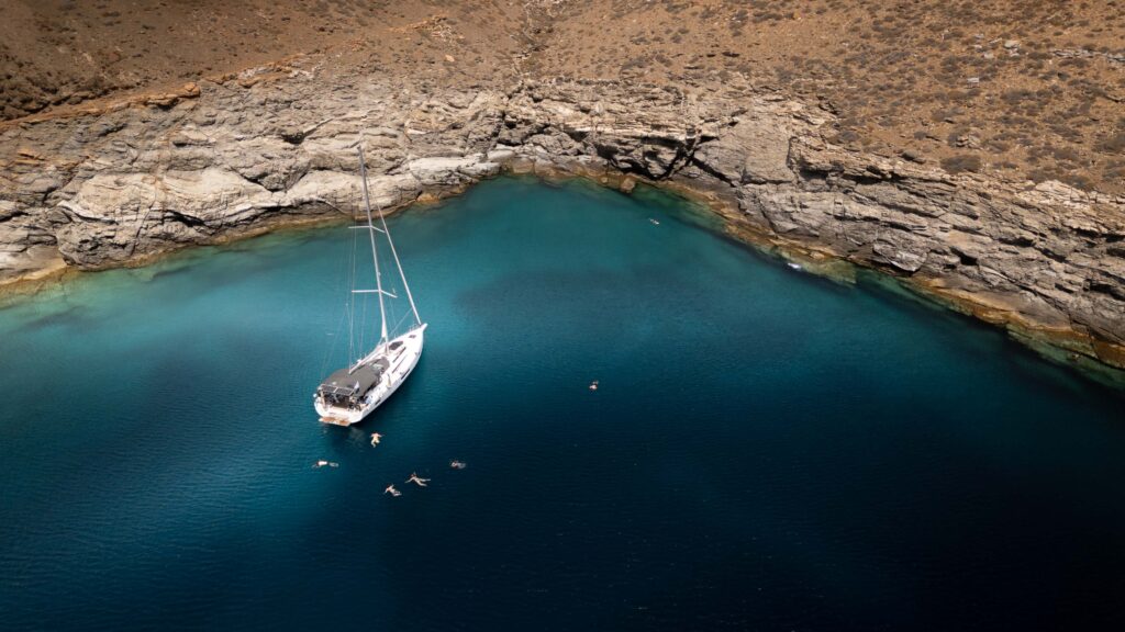 A sailing yacht anchored off a Cyclades island with whitewashed houses and blue Aegean water