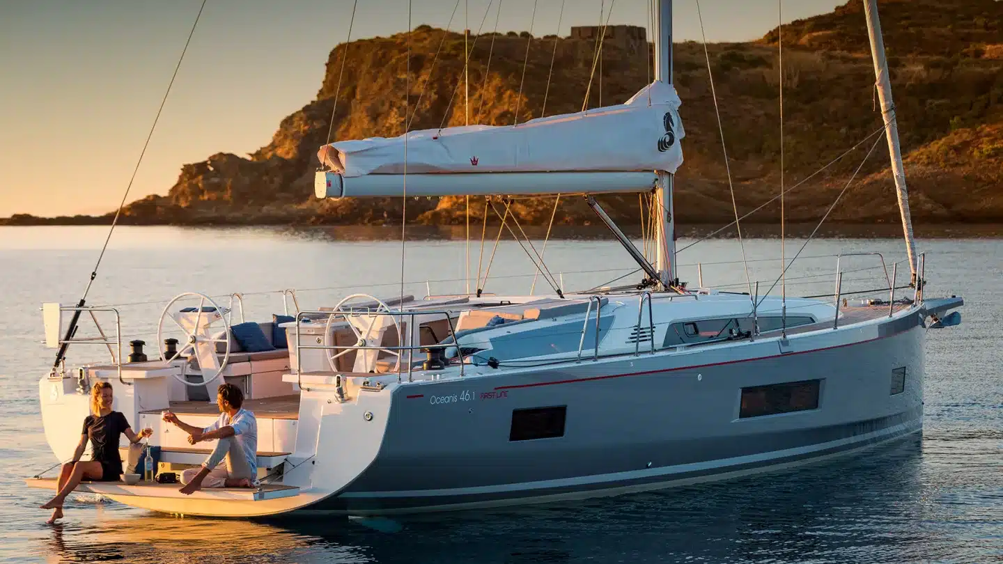A couple relaxing on the stern of a sailing yacht at sunset