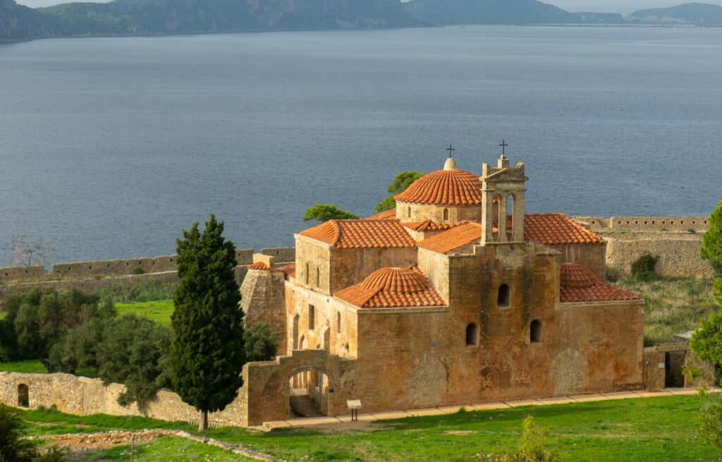 A serene view of a historic stone church near the sea in Pylos, Greece. segeln peloponnes 7-tage-törnvorschlag