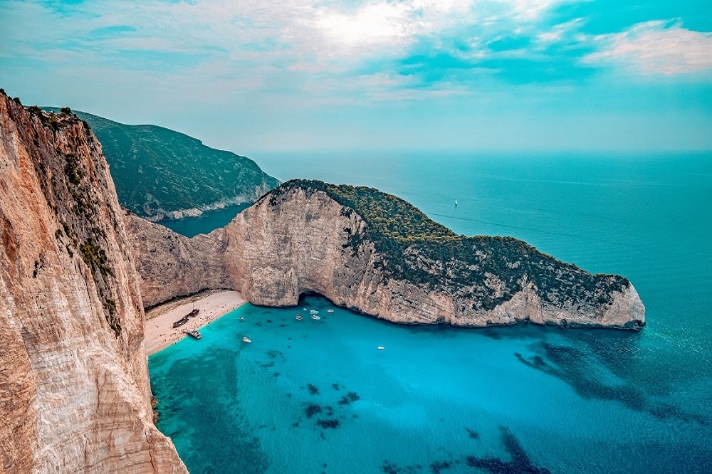 Eine atemberaubende Luftaufnahme des Strandes Navagio auf der griechischen Insel Zakynthos mit seinem berühmten Schiffswrack, den weißen Klippen und dem azurblauen Wasser während eines Segelurlaubs.